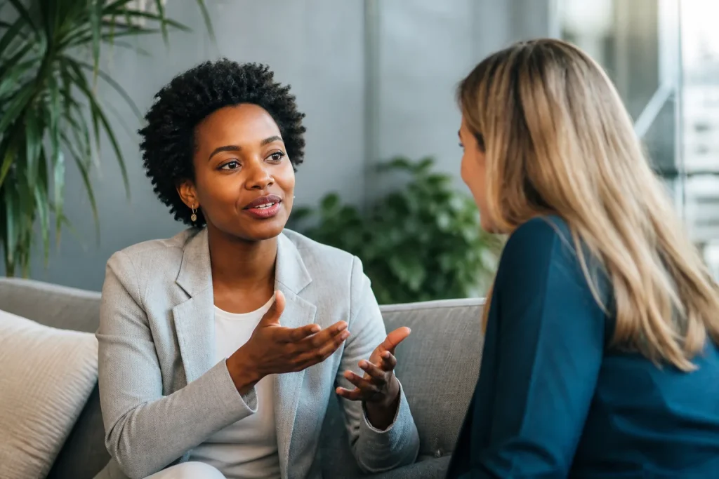 Two professionals in animated discussion, one gesturing emphatically while the other listens attentively, soft warm light highlights their focus.